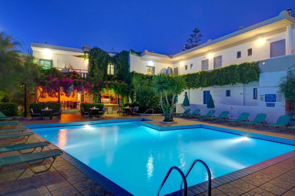 Sofia Hotel in Plakias, Rethymno, Crete, featuring a brightly lit swimming pool surrounded by lush greenery and a charming courtyard."