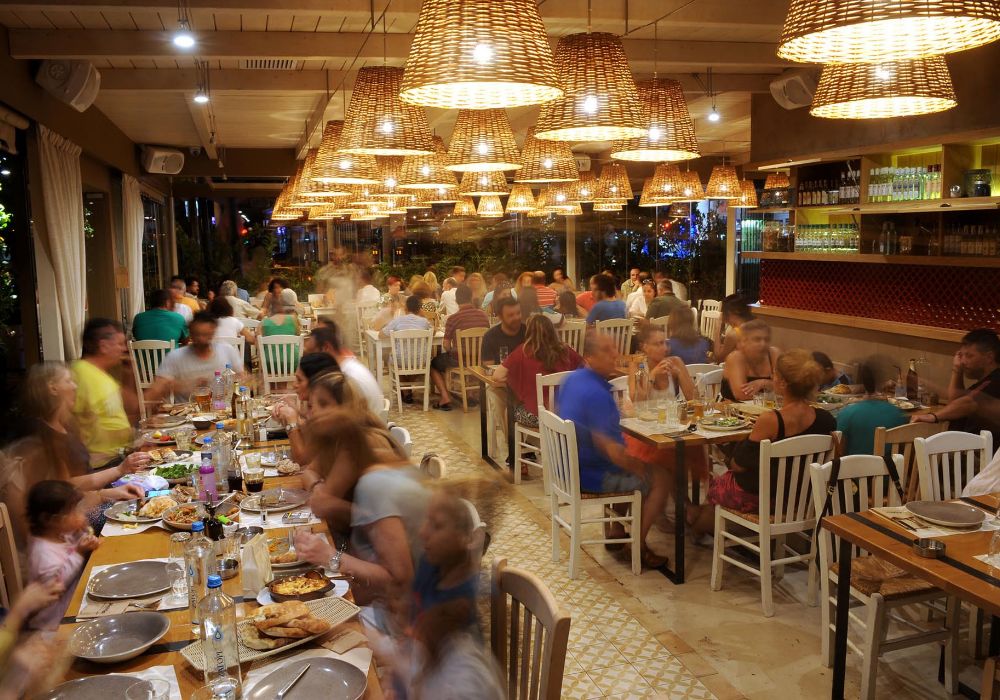 Busy restaurant interior with people enjoying a meal under warm lighting in Paleo Faliro.