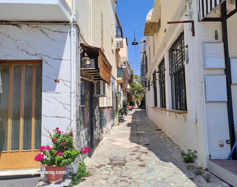 Narrow cobblestone alleyway in a residential area of Athens, lined with charming houses and plants.