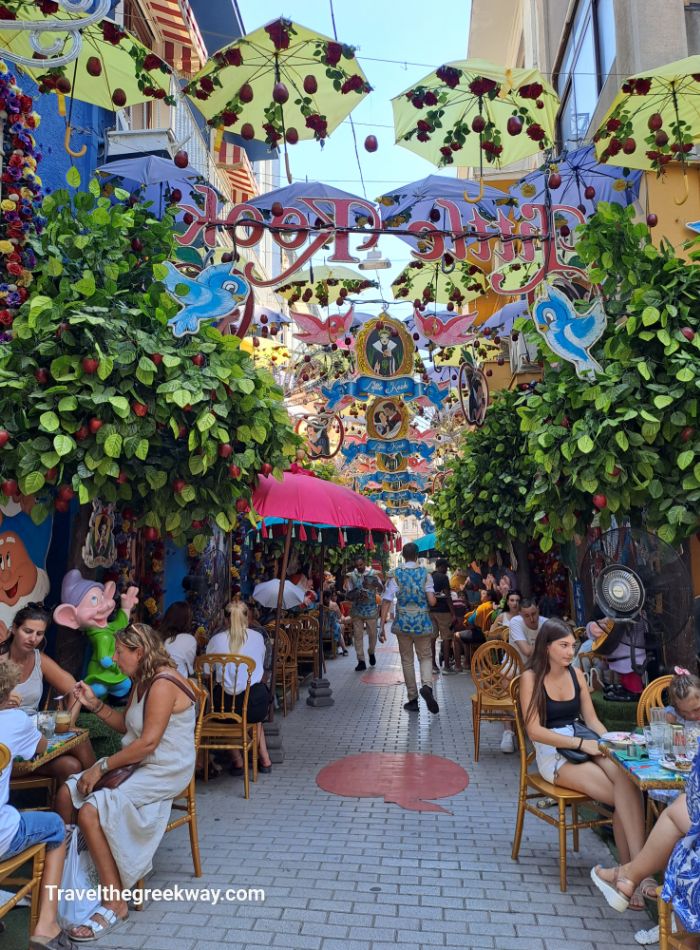 A whimsical scene at Little Kook café in Psiri, Athens, filled with colorful decorations, umbrellas, and vibrant seating areas.