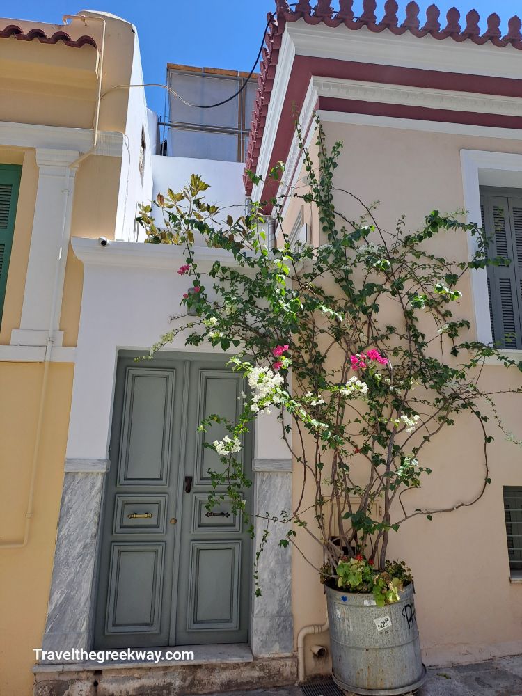 A picturesque street in Plaka, Athens, with a neoclassical house adorned with vibrant bougainvillea, capturing the essence of old Athens.