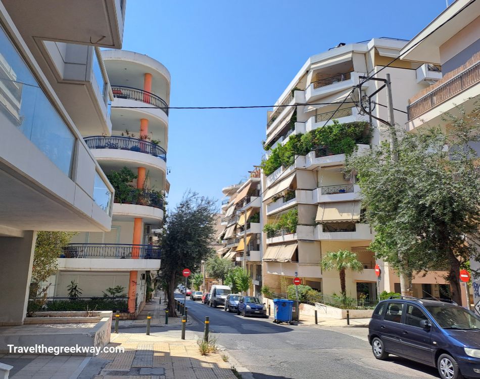  residential street in Athens with modern apartments and balconies covered in greenery.