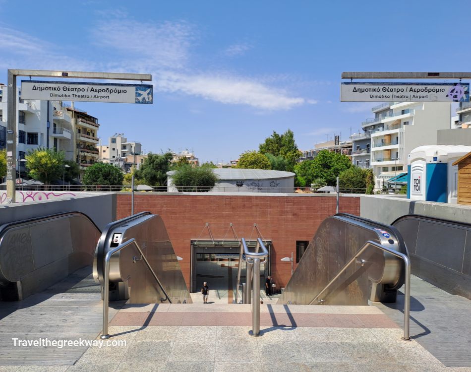 Entrance to the Gkazi metro station in Athens, labeled "Dimotiko Theatro / Airport," with modern urban surroundings.