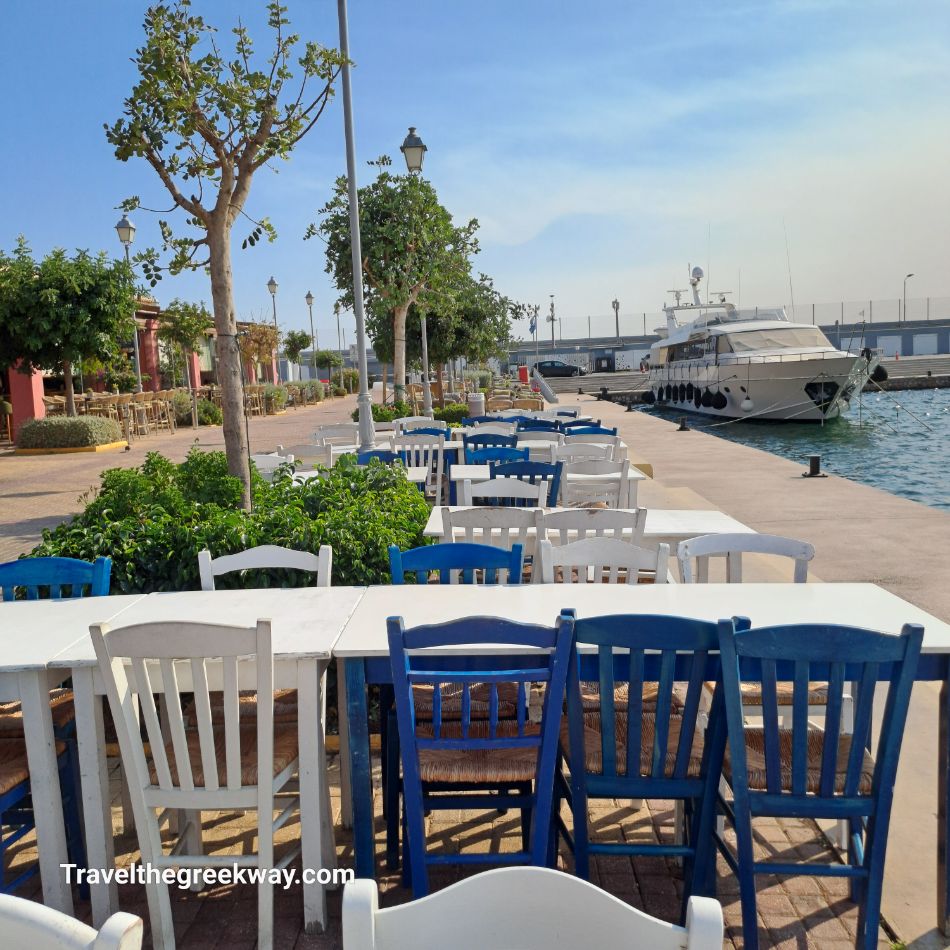 A charming setup of blue and white chairs and tables outside Nisos restaurant, overlooking the marina and the docked yachts.