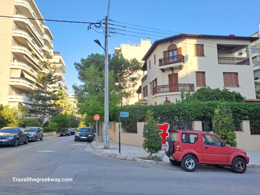 A quiet residential street in Paleo Faliro, featuring modern apartment buildings and a few parked cars.