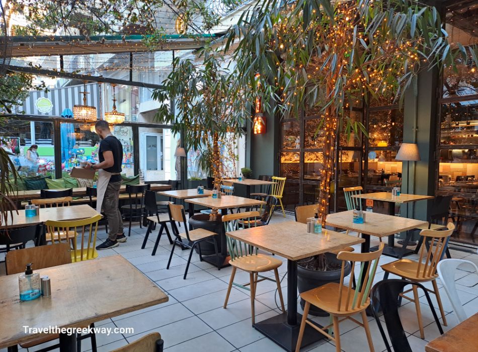 Cozy outdoor dining area at a restaurant in Paleo Faliro, surrounded by greenery and fairy lights.