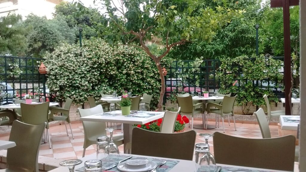 Outdoor garden seating area at a restaurant in Paleo Faliro, with lush plants and neatly set tables.