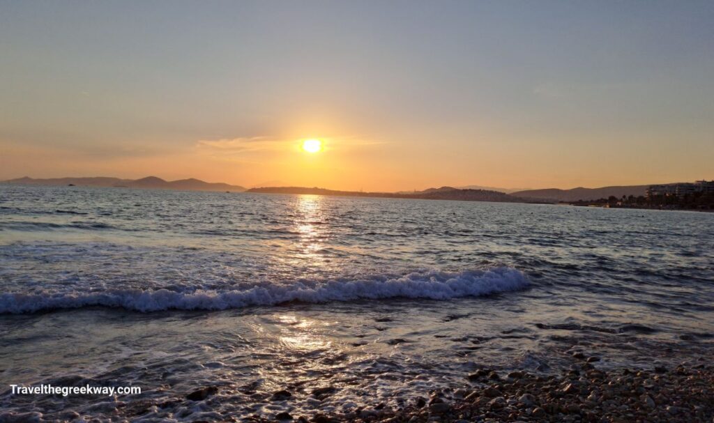 Sunset over the sea in Athens Riviera, with gentle waves lapping the shore.