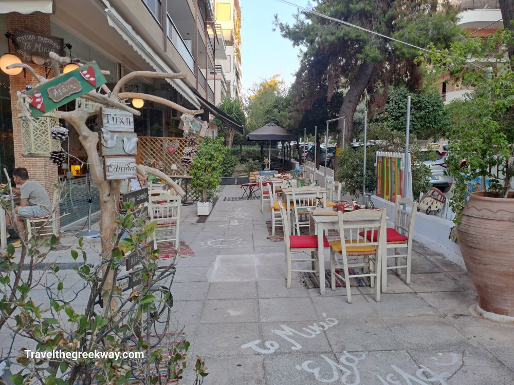 Charming outdoor seating area at To Mikio tavern in Paleo Faliro, decorated with rustic signs and plants.