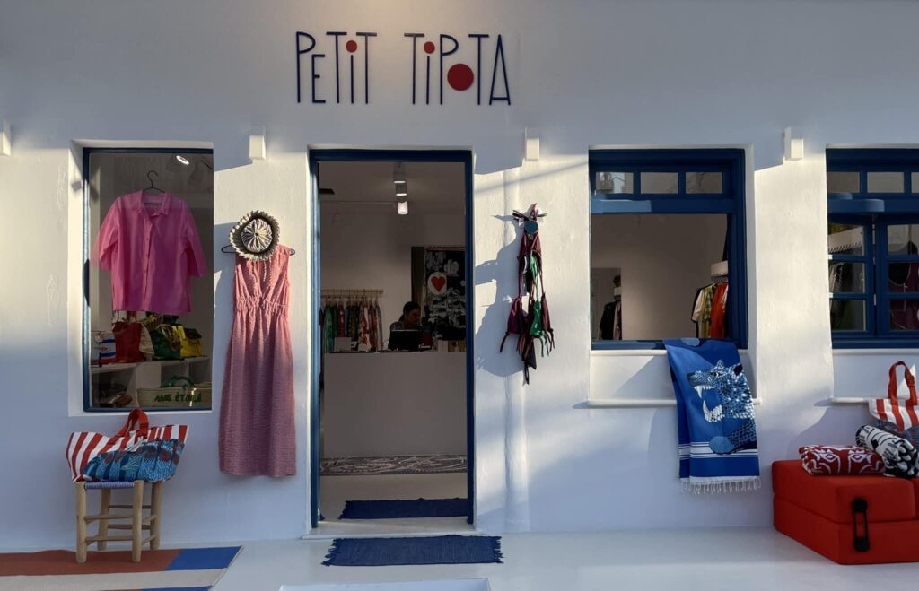 A stylish boutique shop called 'Petit Tipota' in Paros, featuring colorful fashion items displayed in the window.