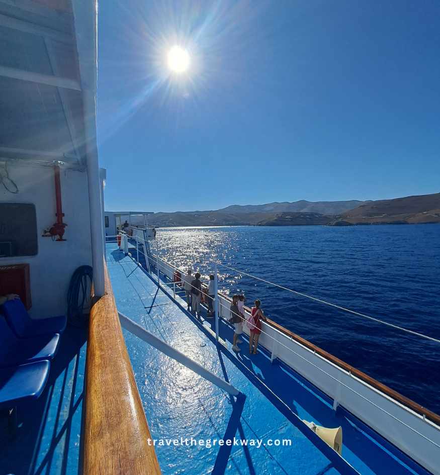 Passengers enjoying sea views from a ferry deck while sailing between the Greek islands in summer.
