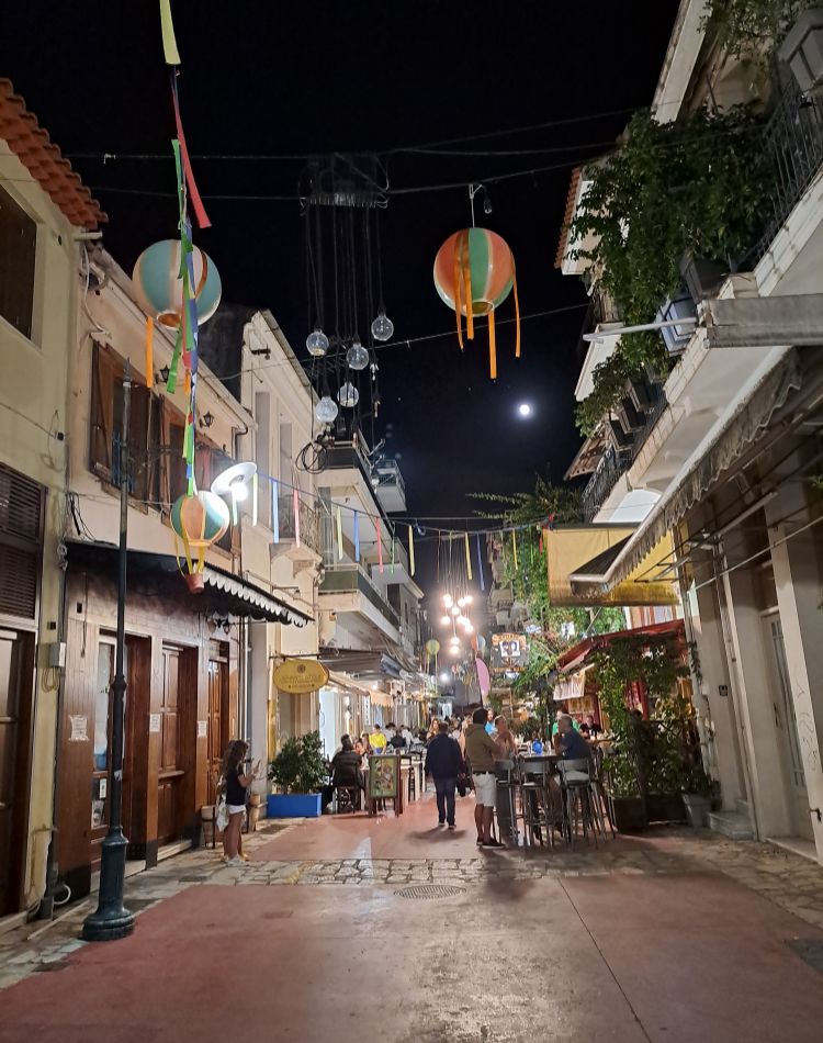 Bustling night scene in Kalamata, Greece, with decorated streets, lights, and people enjoying the vibrant atmosphere.