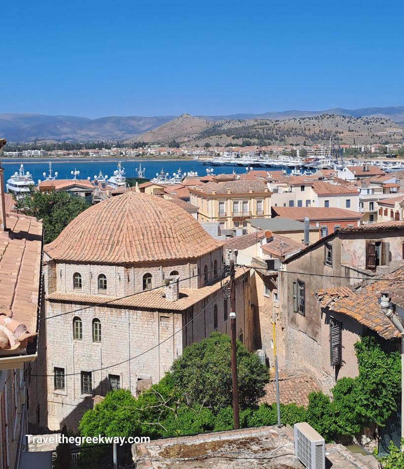 Scenic view of Nafplio’s old town with historic buildings and the harbor in the background under a clear blue sky.