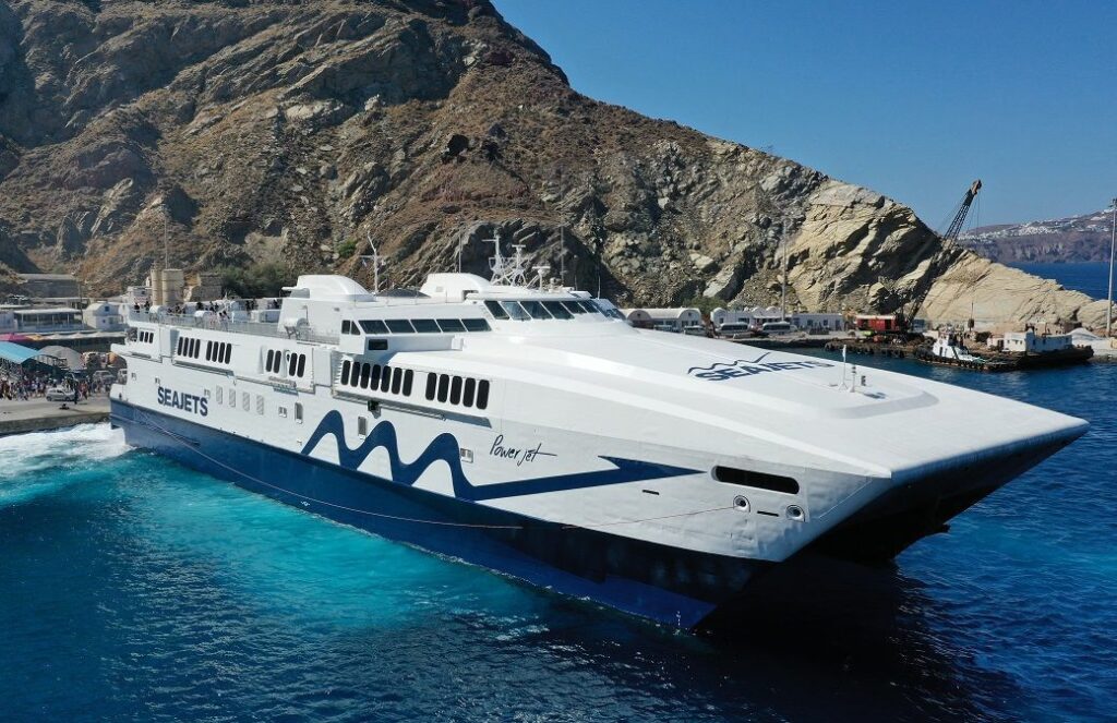 SeaJets high-speed ferry docking at Santorini port with a backdrop of rugged cliffs and a bustling harbor