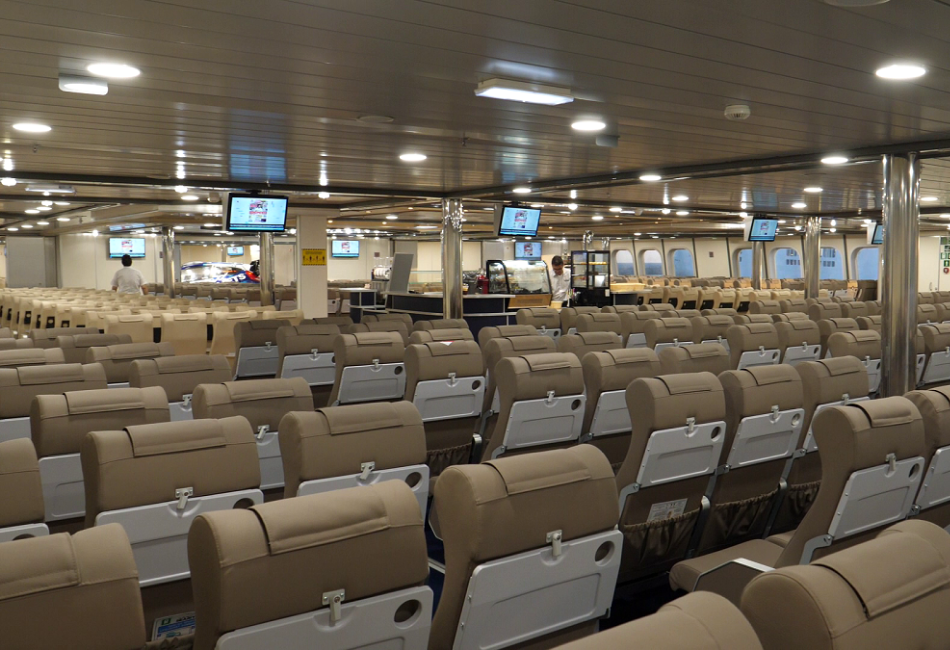 Interior of SeaJets Power Jet ferry with rows of comfortable seating, TV screens, and bright, spacious design for passenger comfort.