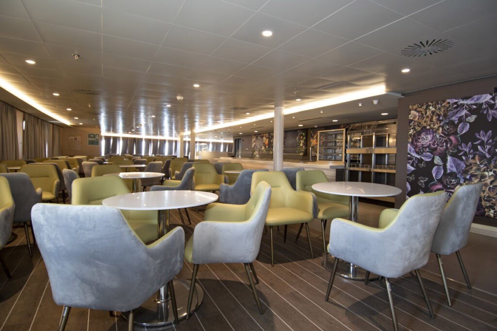 Modern and stylish lounge area on a SeaJets ferry, with comfortable seating and tables, offering a relaxed travel experience.