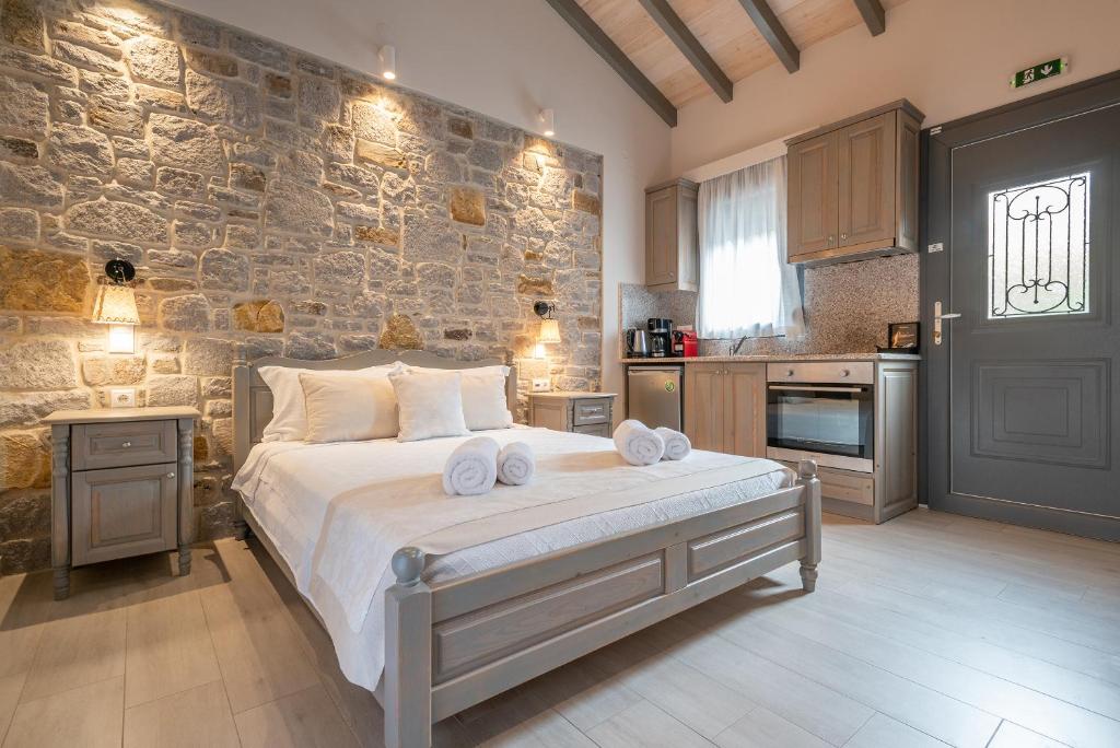 Cozy hotel room in Amygdalies, Lemnos, featuring a stone wall, wooden furniture, and a small kitchen area.