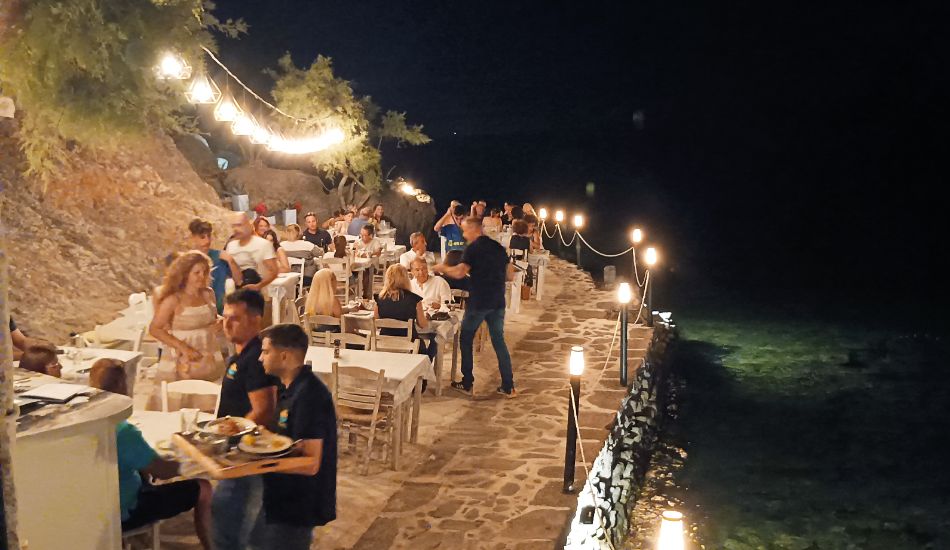 Nighttime dining at the foot of the castle hill in Lemnos, with tables set along the waterfront path.