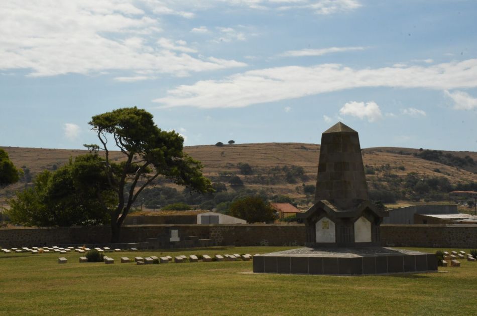 Military cemetery in Lemnos, with a memorial monument and rows of gravestones under a blue sky.