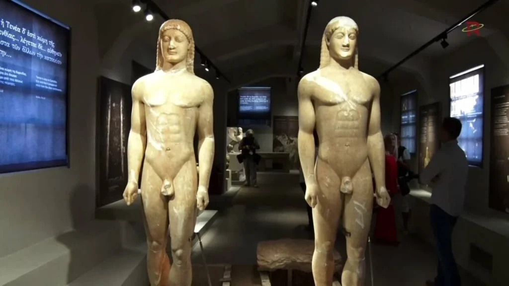 Two kouros statues displayed side by side in the museum, showcasing ancient Greek artistry.