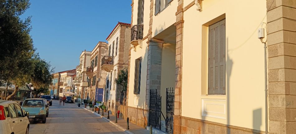 A street in Myrina lined with neoclassical buildings and trees, capturing the charm of the town's architecture.