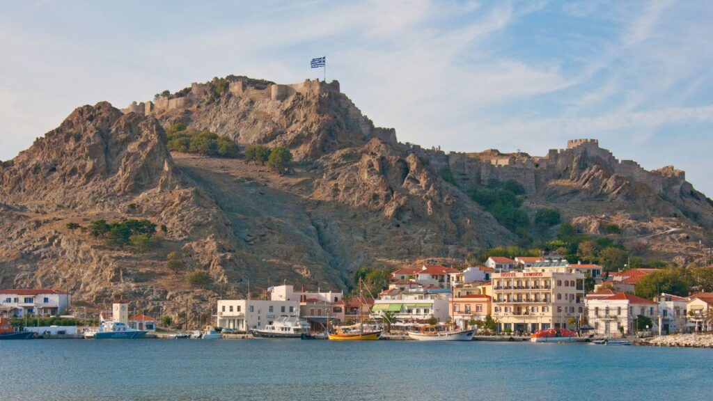 Closer view of Myrina’s waterfront with the Venetian castle towering above, overlooking the charming coastal town.