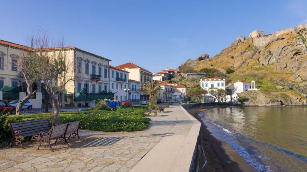 Myrina’s scenic coastal walkway, bordered by historic buildings and offering views of the castle and the calm bay.