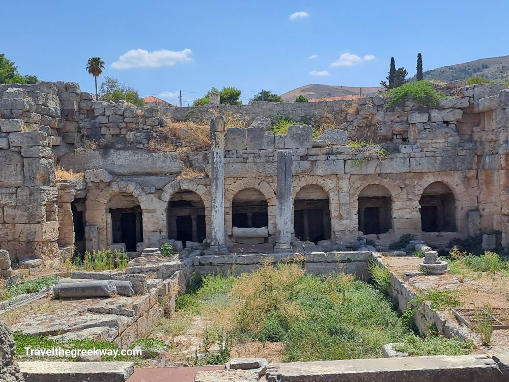 Ruins of the Peirene Fountain, with archways and remnants of ancient Corinthian architecture.