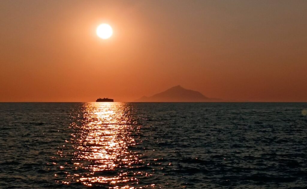 A stunning sunset over the Aegean Sea as seen from Myrina, with Mount Athos visible in the distance.