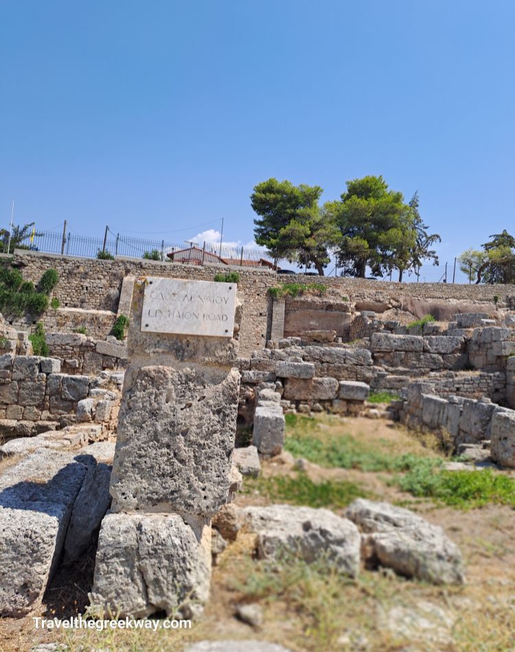  Historical marker for Lechaion Road with ancient ruins and trees in the background.