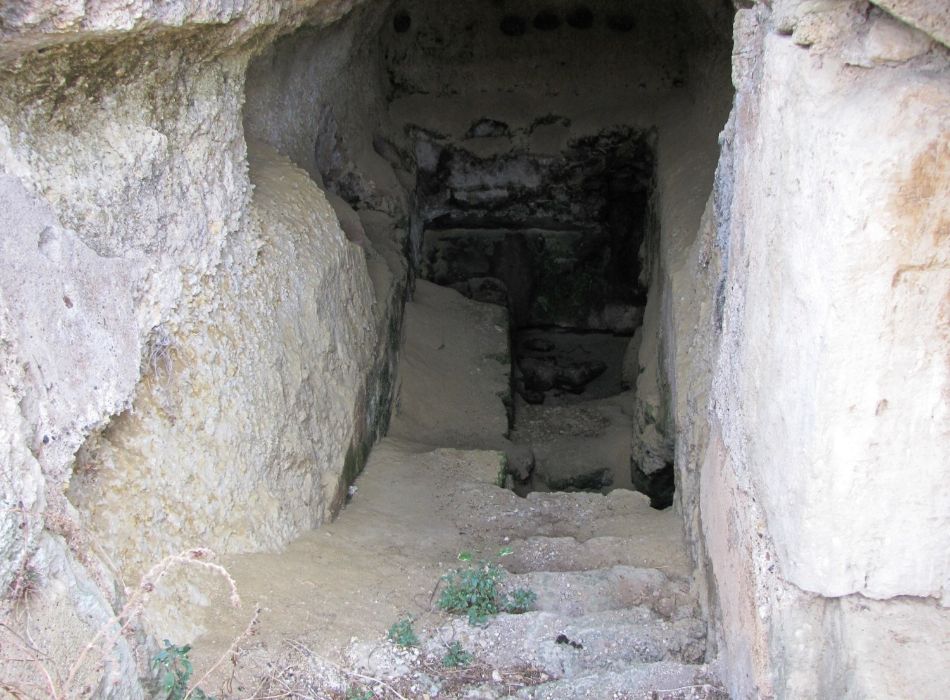 A view of the entrance to an underground fountain in Ancient Corinth with steps descending into the rock.