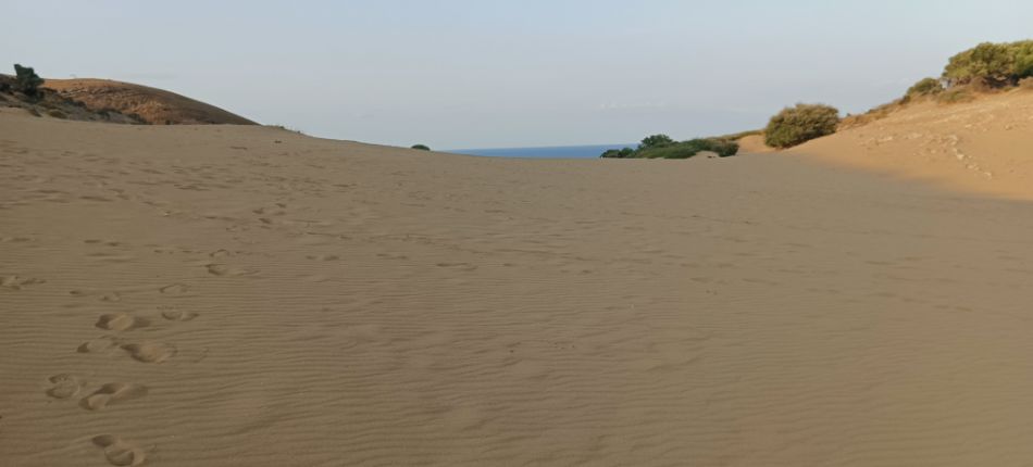 A vast stretch of sand dunes on Lemnos, with a view of the sea in the distance.