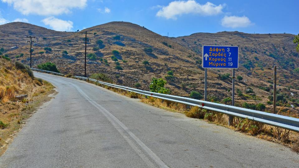 Country road in Lemnos island with a sign pointing to nearby villages like Dafni, Sardes, and Kornos.