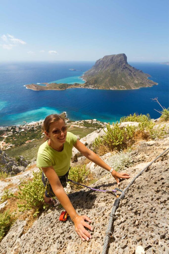 Woman rock climbing on Kalymnos with a stunning view of the Aegean Sea and nearby islands.