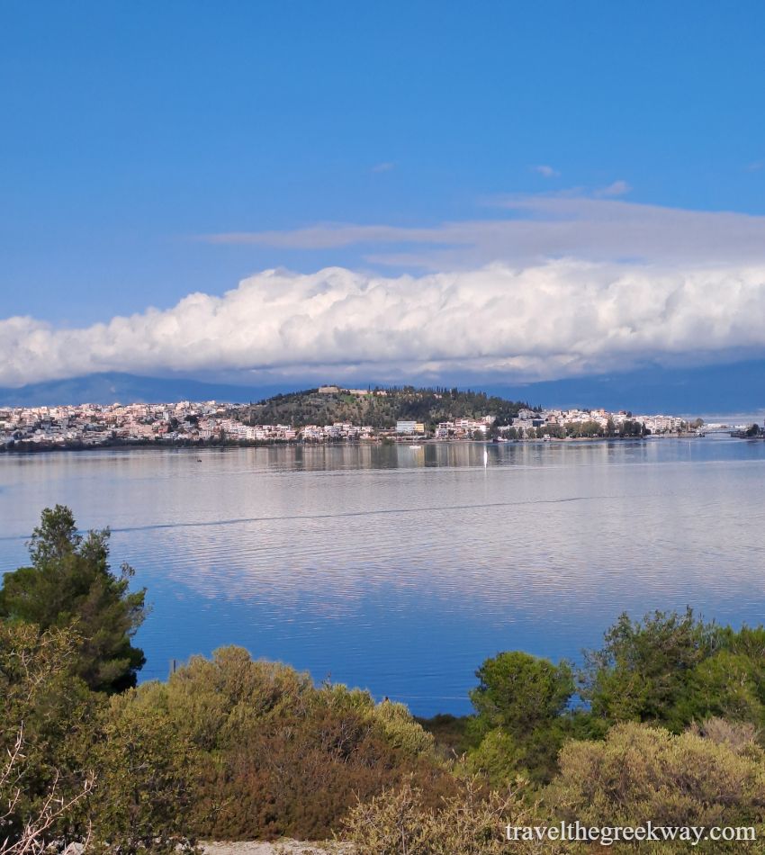 Scenic view of Chalkida, Evia, with calm sea and dramatic cloud formations under a blue sky.