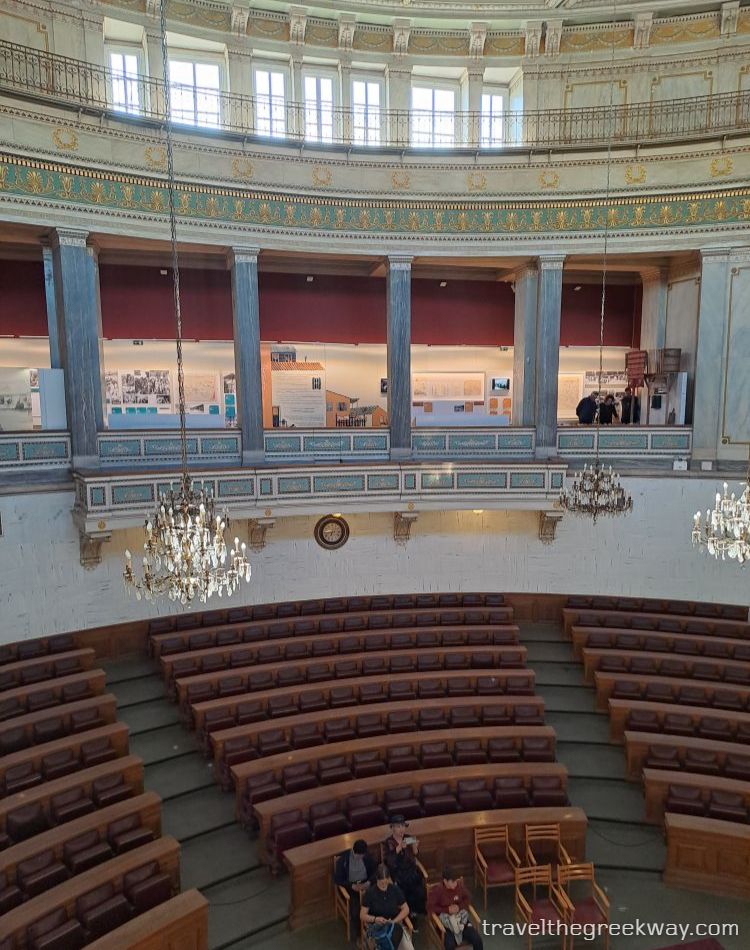 Interior view of the old parliament hall with chandeliers and balconies at the National Historical Museum of Athens.