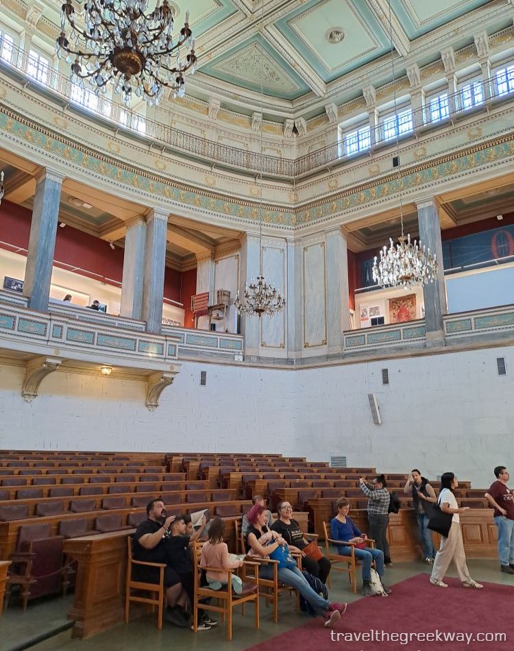 Visitors seated inside the old parliament chamber at the National Historical Museum in Athens.