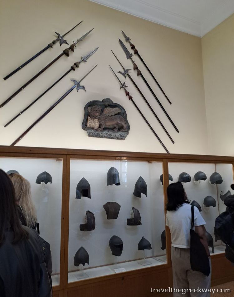 Display of medieval helmets and weapons inside the National Historical Museum of Athens.