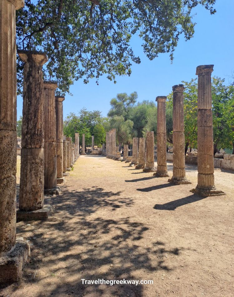 Row of ancient stone columns at Olympia under the summer sun.