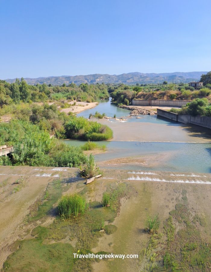 View of the Alpheios River with greenery and mountains in the background.
