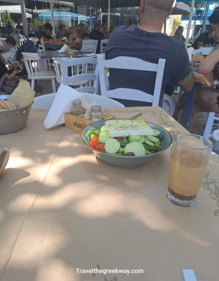 Greek salad and Greek coffee on a taverna table with people dining in the background.