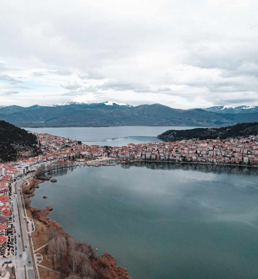Panoramic view of Kastoria, Greece, built along Lake Orestiada with mountains rising across the lake.