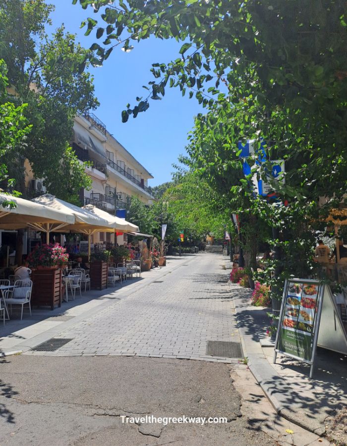 Shady pedestrian street in Olympia town lined with cafés and restaurants.