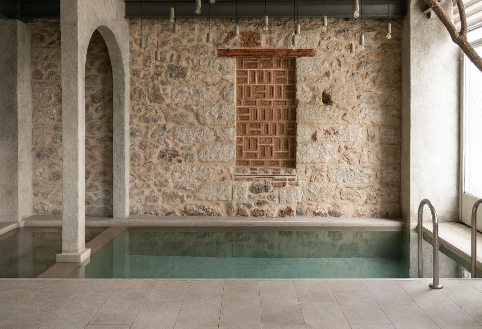 Indoor boutique hotel pool in Athens with stone walls and elegant design.