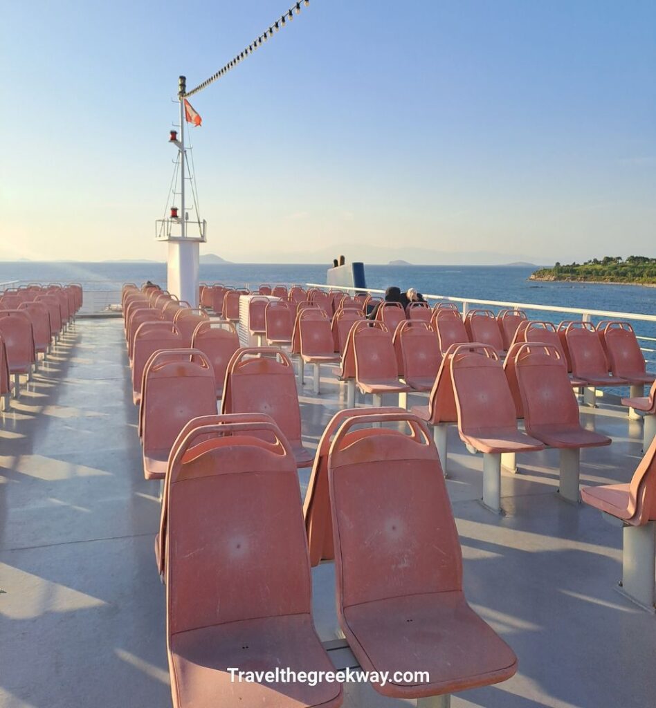 Outdoor ferry deck with rows of empty seats facing the sea under warm evening light.