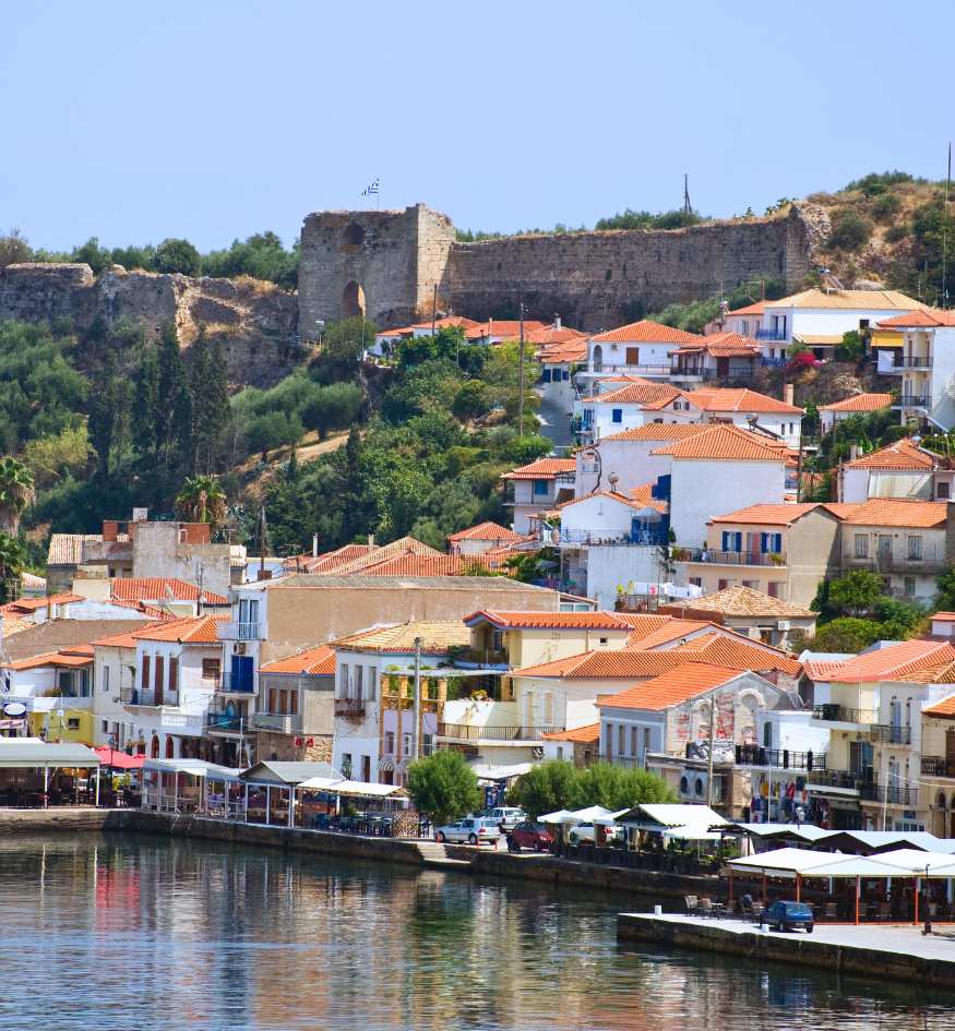 The picturesque waterfront of Koroni in Messenia, featuring traditional colorful buildings and the Venetian castle on the hill.