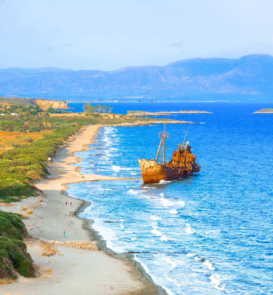 The rusted hull of the Dimitrios shipwreck resting on the golden sands of Valtaki Beach near Gytheio, Laconia.
