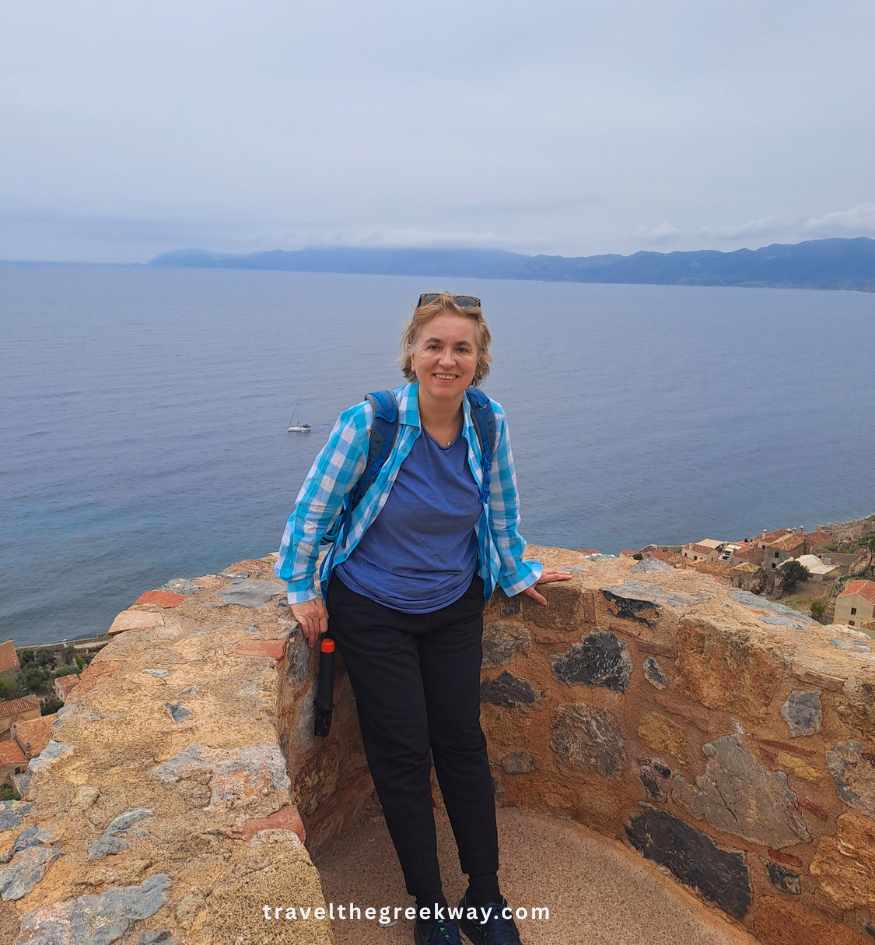 Evgenia enjoying panoramic sea views from fortress walls in Monemvasia, Peloponnese Greece.