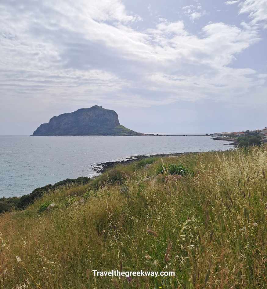 The massive fortified rock of Monemvasia seen from a grassy field in Peloponnese Greece.