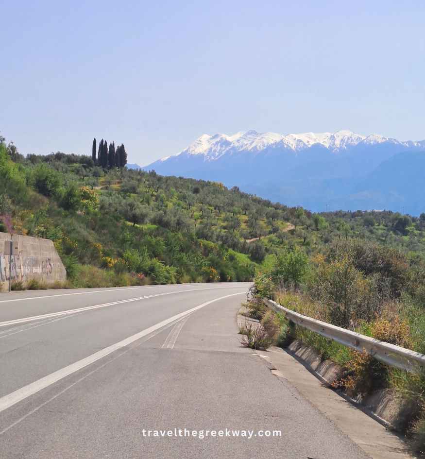 Scenic asphalt highway leading through hills toward distant mountains in Peloponnese Greece.